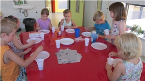 Kinder sitzen um einen Tisch und experimentieren mit Wasser.