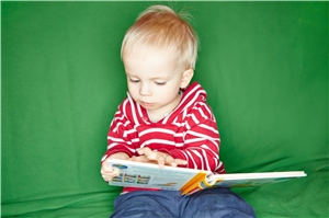 ein sitzendes kleines Kind mit einem offenen Bilderbuch