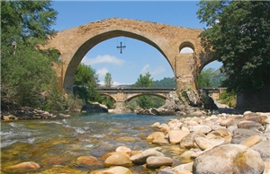 Brücke unter der an Fluß hindurch fließt. Unter der Brücker hängt ein Kreuz.