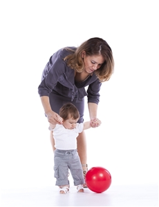 Frau führt kleines Kind an den Händen - roter Ball.