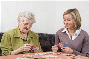Frau spielt mit Bewohnerin Karten.