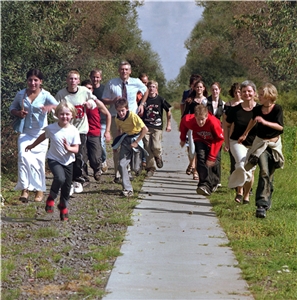 Gruppe von Erwachsenen und Kindern die auf einem Weg rennen.
