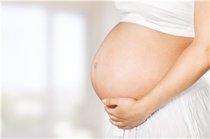 Eine schwangere Frau umfasst mit ihren Händen ihren Bauch.