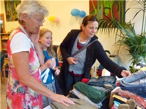 Zwei Frauen und ein Kind schauen sich Kleidung an. Tauschparty 2016_1
