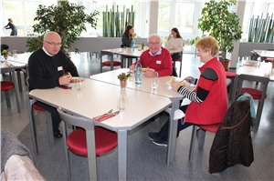 Nach der Spendenübergabe sitzen die Ehrenamtlichen Kurt und Heide Wolf zusammen mit Pfarrer Josef Szuba (links) am Tisch und essen die liebevoll für die Ehrenamtlichen zubereitete Bohnensuppe.