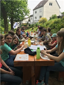 Die Jungen und Mädchen nach getaner Arbeit beim Essen und Trinken an einem langen Tisch. Die Jungen und Mädchen nach getaner Arbeit beim Essen und Trinken an einem langen Tisch.