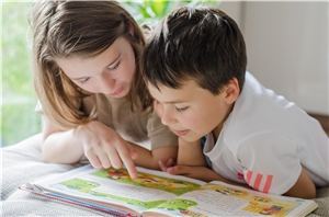 Eine junge Frau unterstützt einen Jungen beim Lernen.