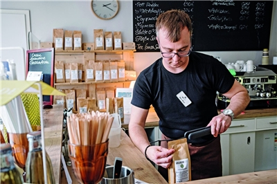 Ein Mitarbeiter der Goslarschen Höfe hantiert an der Kaffeetheke mit einer Kaffeebohnen-Packung.