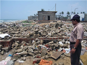 Ein Mann steht nach der Tsunami-Katastrophe vor den Trümmern eines Gebäudes