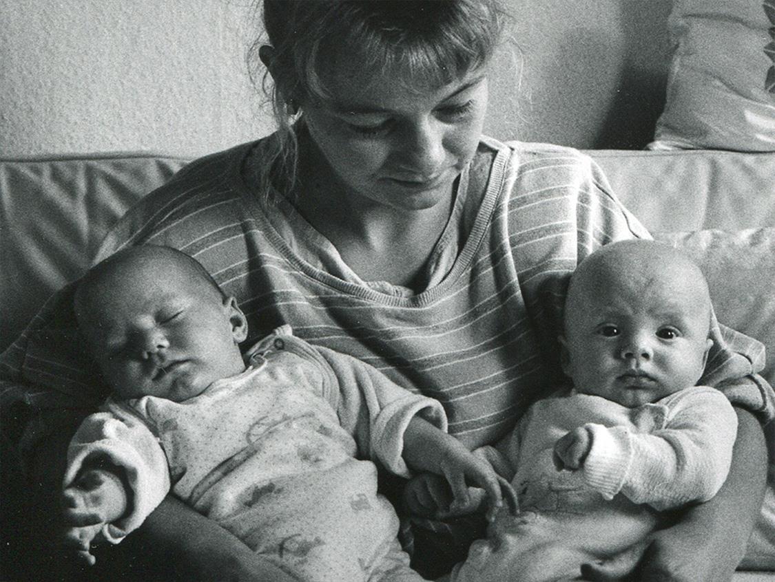 Frau hält zwei Babies auf ihrem Arm. 
