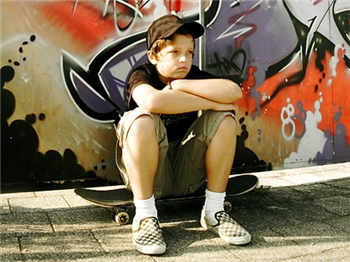Frustrierter Junge sitzt auf einem Skateboard