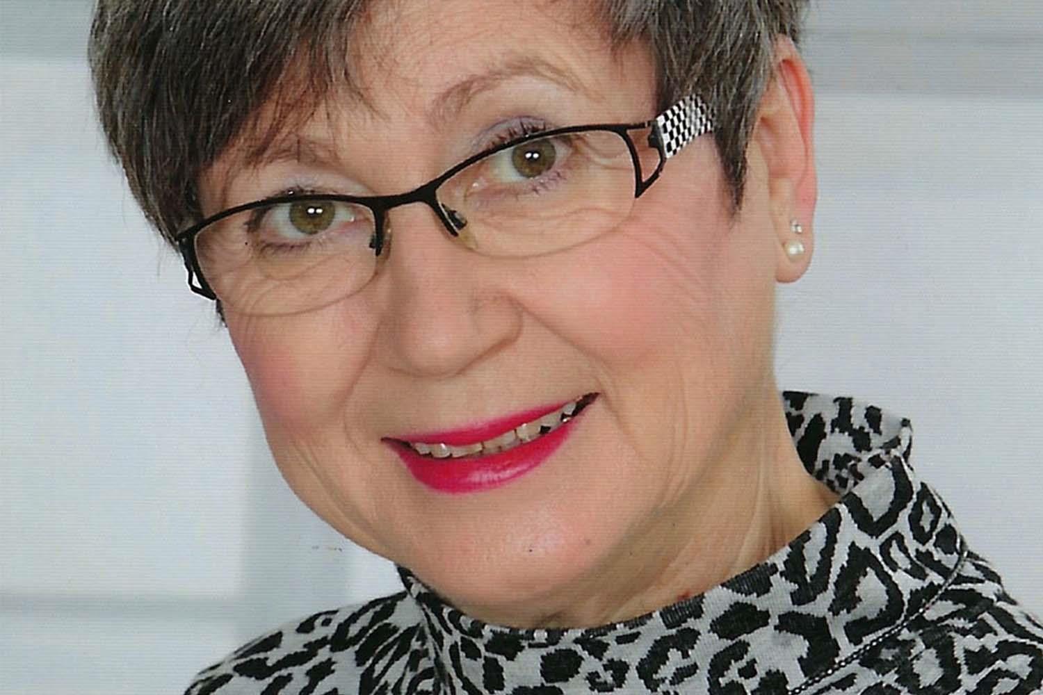 Eine ältere Damen mit grauen kurzen Haar und Brille.