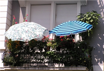 Balkon einer Altbau-Wohnung mit zwei Sonnenschirmen.