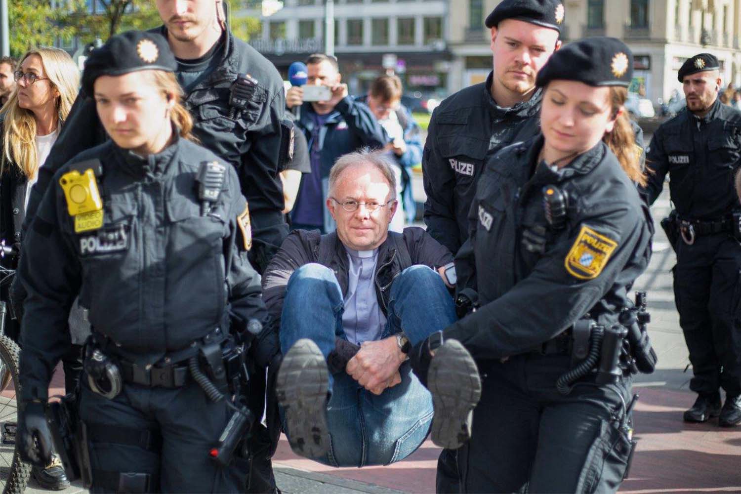 Ein Mann mittleren Alters wird von  Polizei gefasst. Er wird von Vier PolizistInnen mitgenommen.