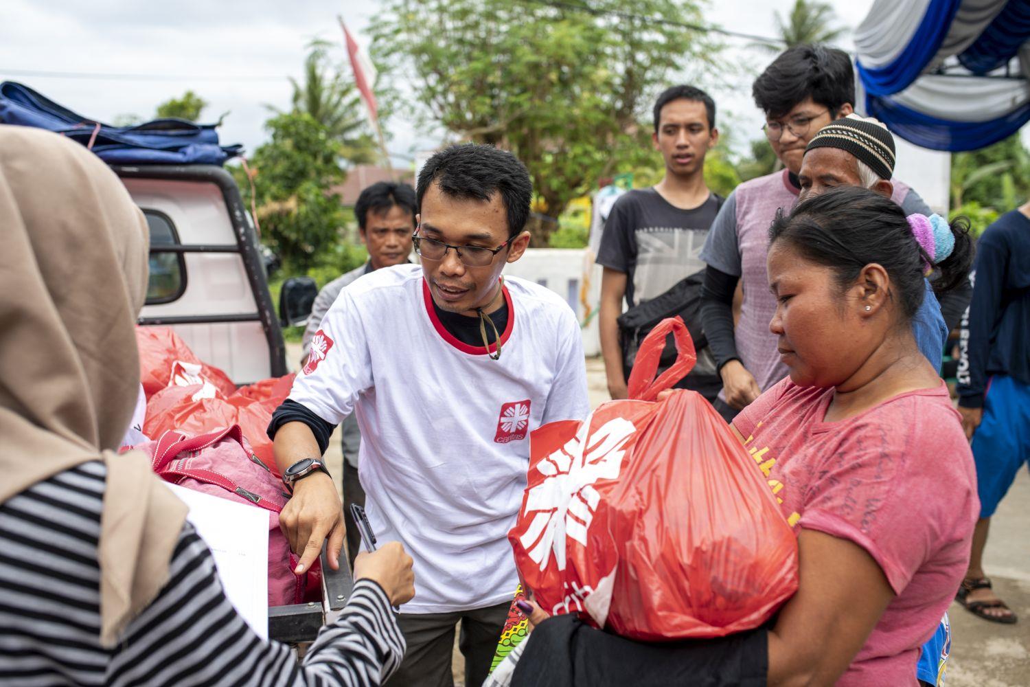 Junger Helfer verteilt Hilfspakete an Katastrophenopfer in Indonesien 