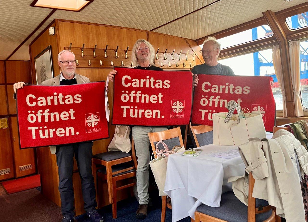 Harald Westbeld, Mathias Thees, Christian Scharf mit halten rote Kampagnenfußmatten 