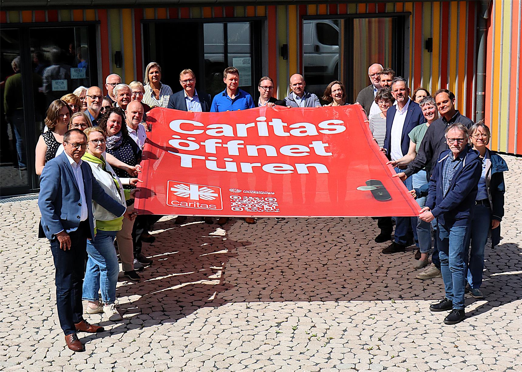 Alle Vorstände halten ein großes rotes Banner in den Händen auf dem steht 