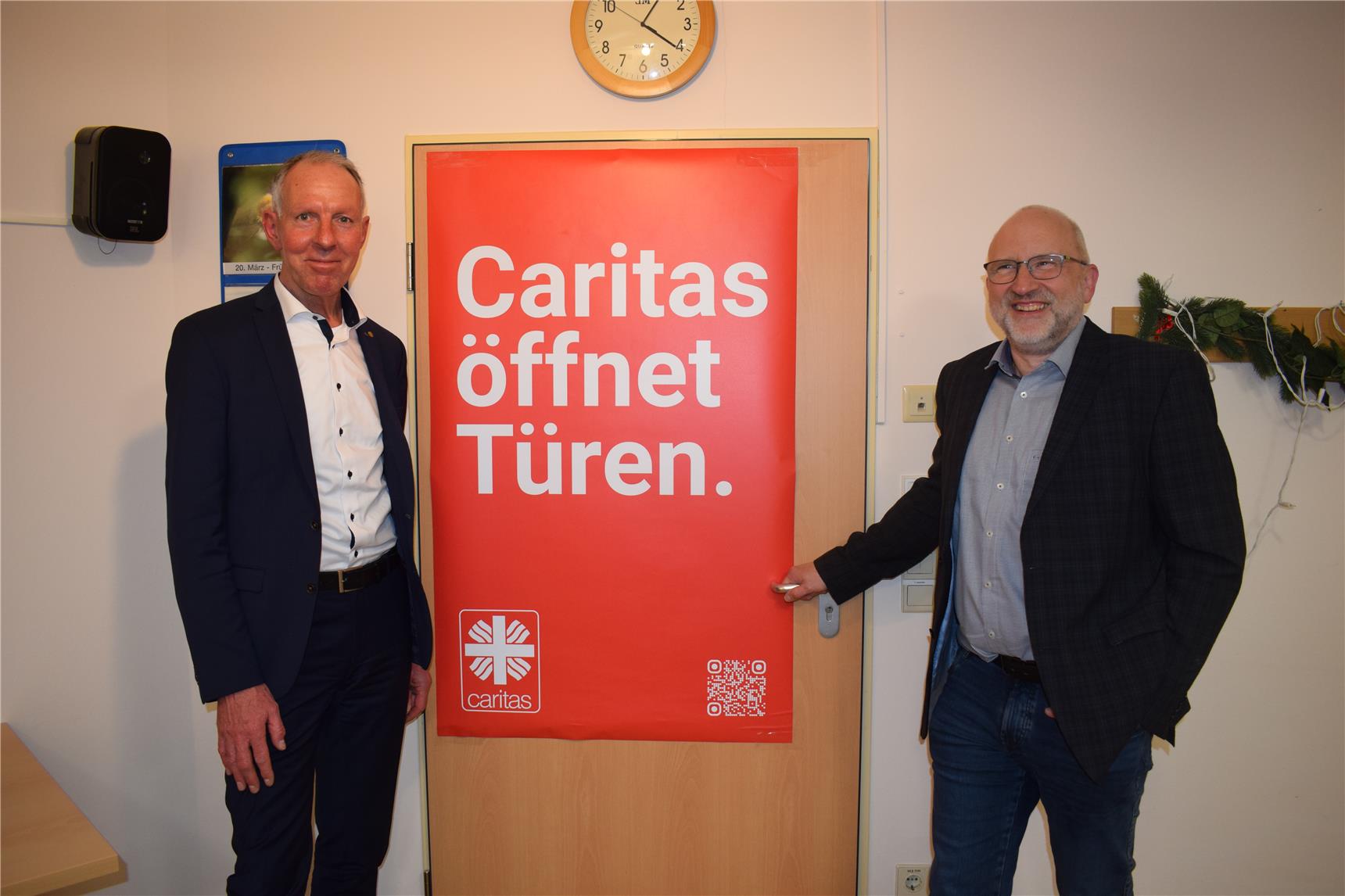 Neben Jens Lehmann (links) steht der Heimleiter Klaus Mildner, zwischen Ihnen die rote Tür in einer Caritas Einrichtung.