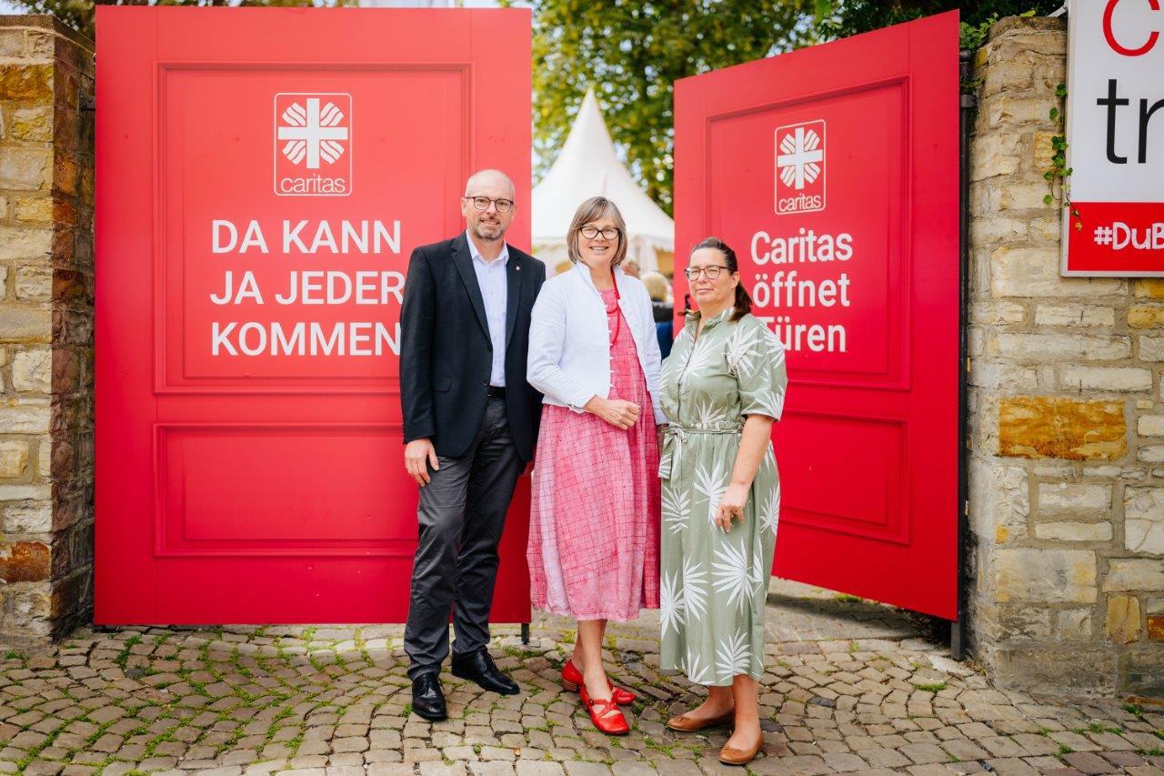 Prominente Vertreter_innen der Caritas vor dem roten Kampagnentor 