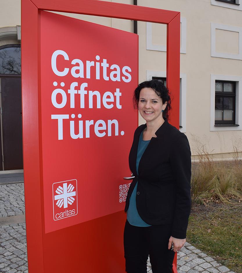 Dr. Judith Thiele, Referentin des Vorstandes für den Caritasverband für das Bistum Dresden-Meißen, geht durch die rote Caritas Tür hindurch.