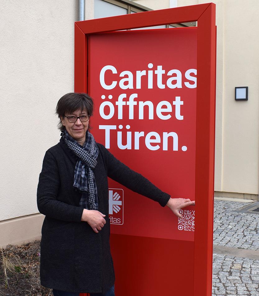 Mechthild Gatter, Abteilungsleiterin Fachberatung und Sozialpolitik für den Caritasverband für das Bistum Dresden-Meißen geht durch die rote Caritas Tür hindurch..