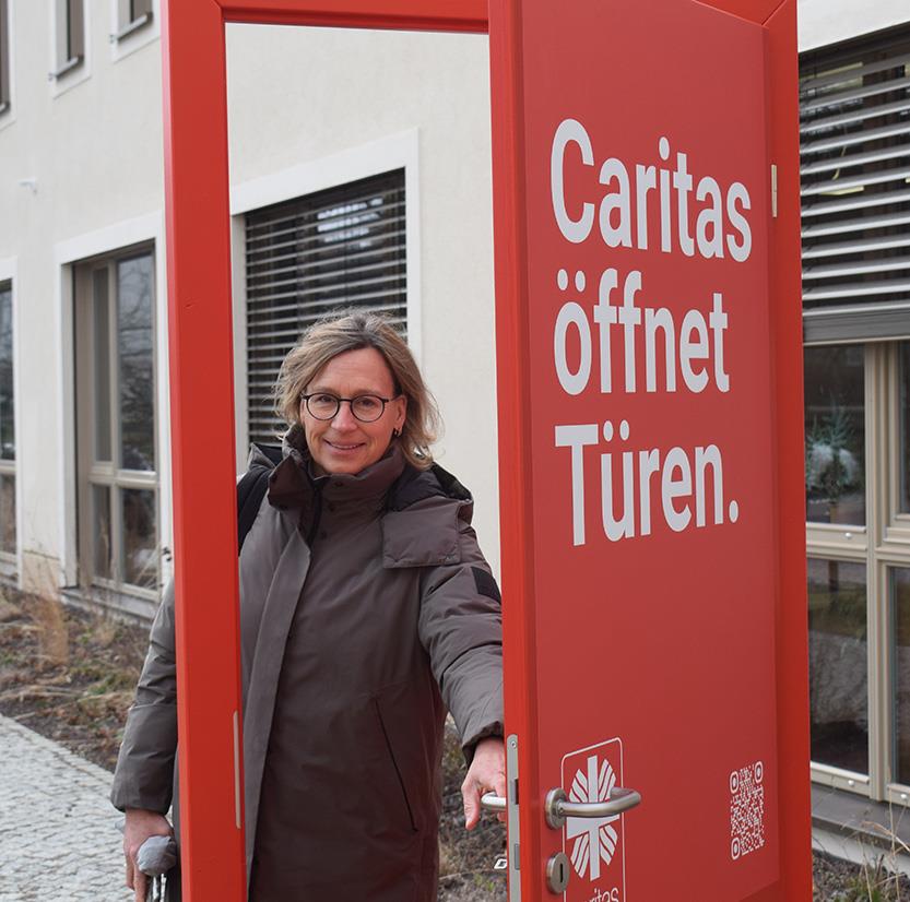 Sabine Geck, Geschäftsführerin Caritasverband Chemnitz geht durch die rote Caritas Tür hindurch..