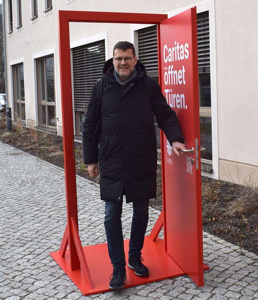 Torsten Bognitz, Geschäftsführer Caritasverband Oberlausitz, geht durch die rote Caritas Tür hindurch..