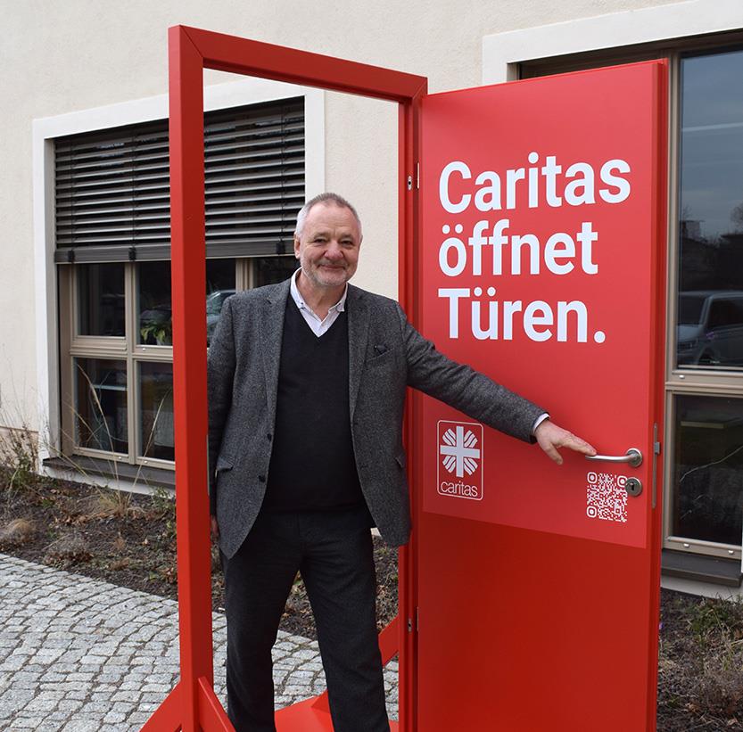 Wolfram Mager, Caritas-Vorstand Personal für das Bistum Dresden-Meißen geht durch die rote Caritas Tür hindurch..