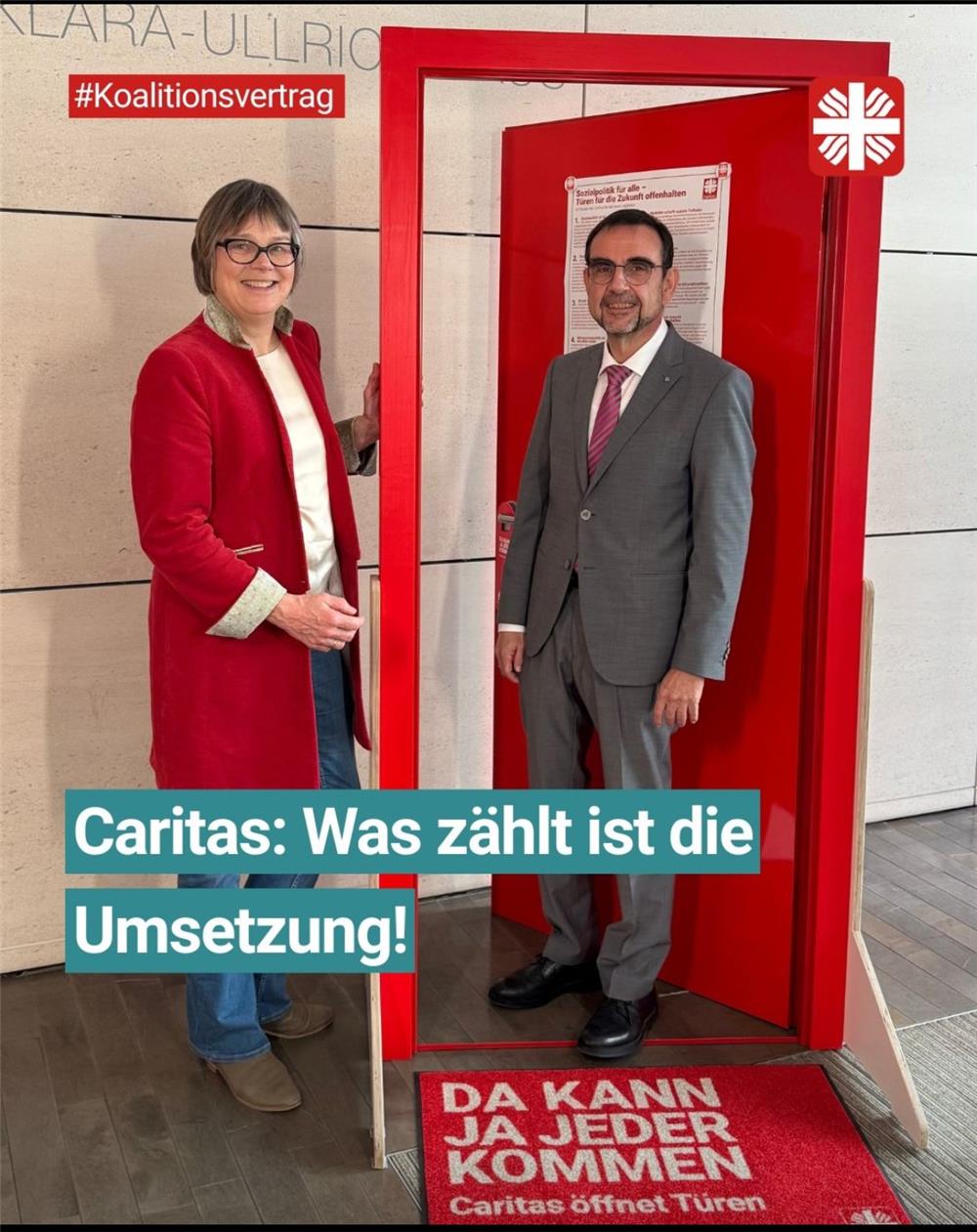 Klaus Holetschek, Fraktionsvorsitzenden der CSU im Bayerischer Landtag, steht in der roten Kampagnentür, neben der Tür Caritas-Präsidentin Welskop-Deffaa. Im Bild der Hashtag Koalitionsvertrag und als Schriftzug 