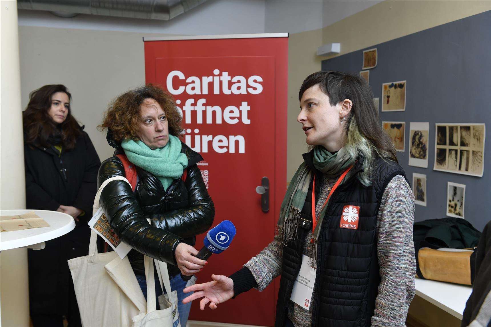 Der Bayrische Rundfunk interviewt eine Mitarbeiterin der Caritas und hält ihr ein Mikrofon hin.