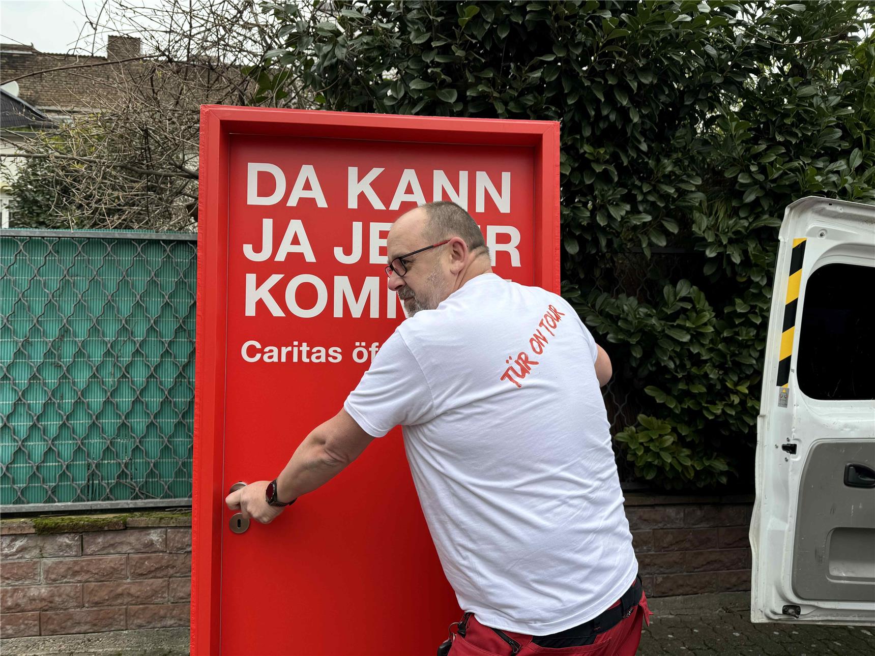 Hausmeister Manolito Haub schiebt die Tür über einen Parkplatz.