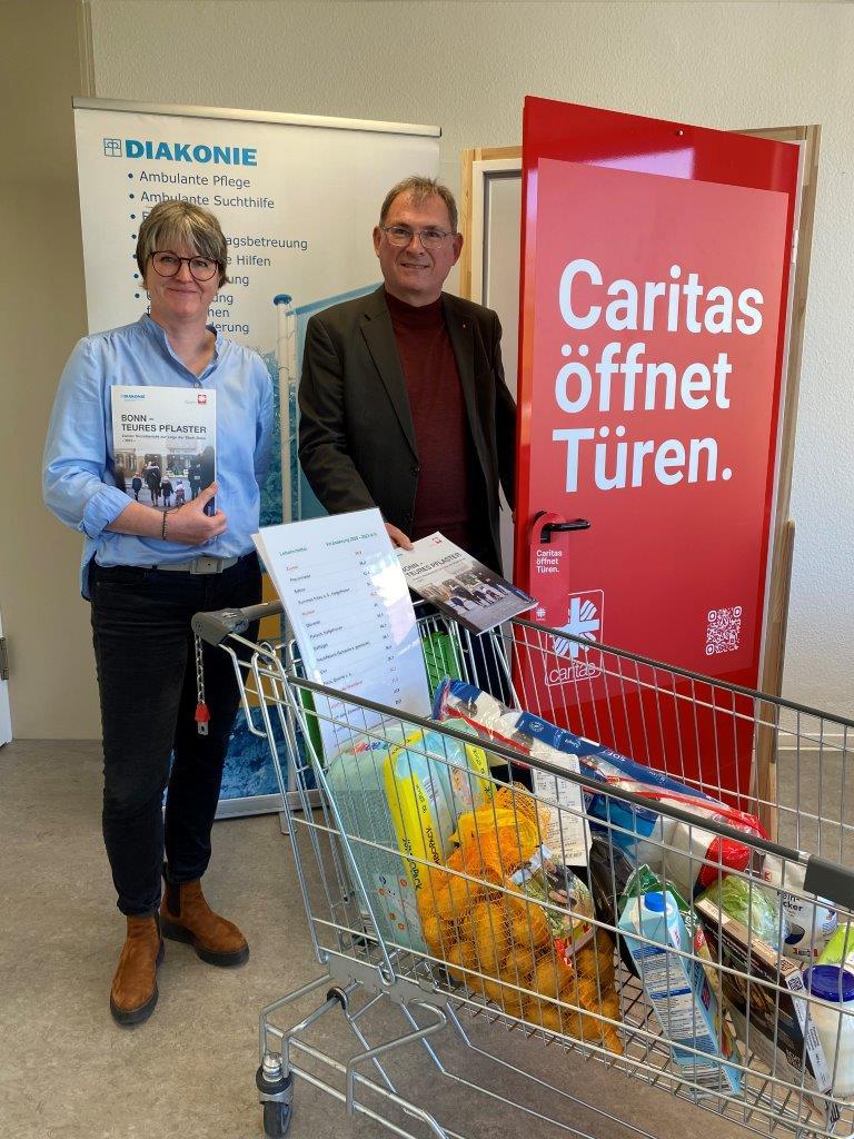 Eine Frau und ein Mann mit einem Einkaufswagen voller Lebensmittel vor der Kampagnentür 