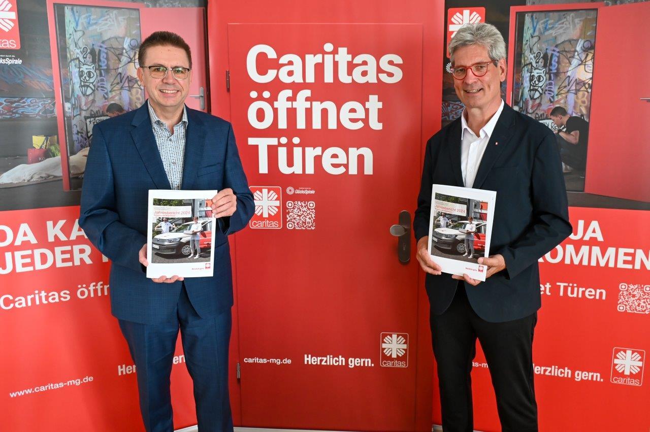 Der Geschäftsbericht des CV Mönchengladbach wird von zwei Herren in Anzug vor dem Kampagnenplakat 