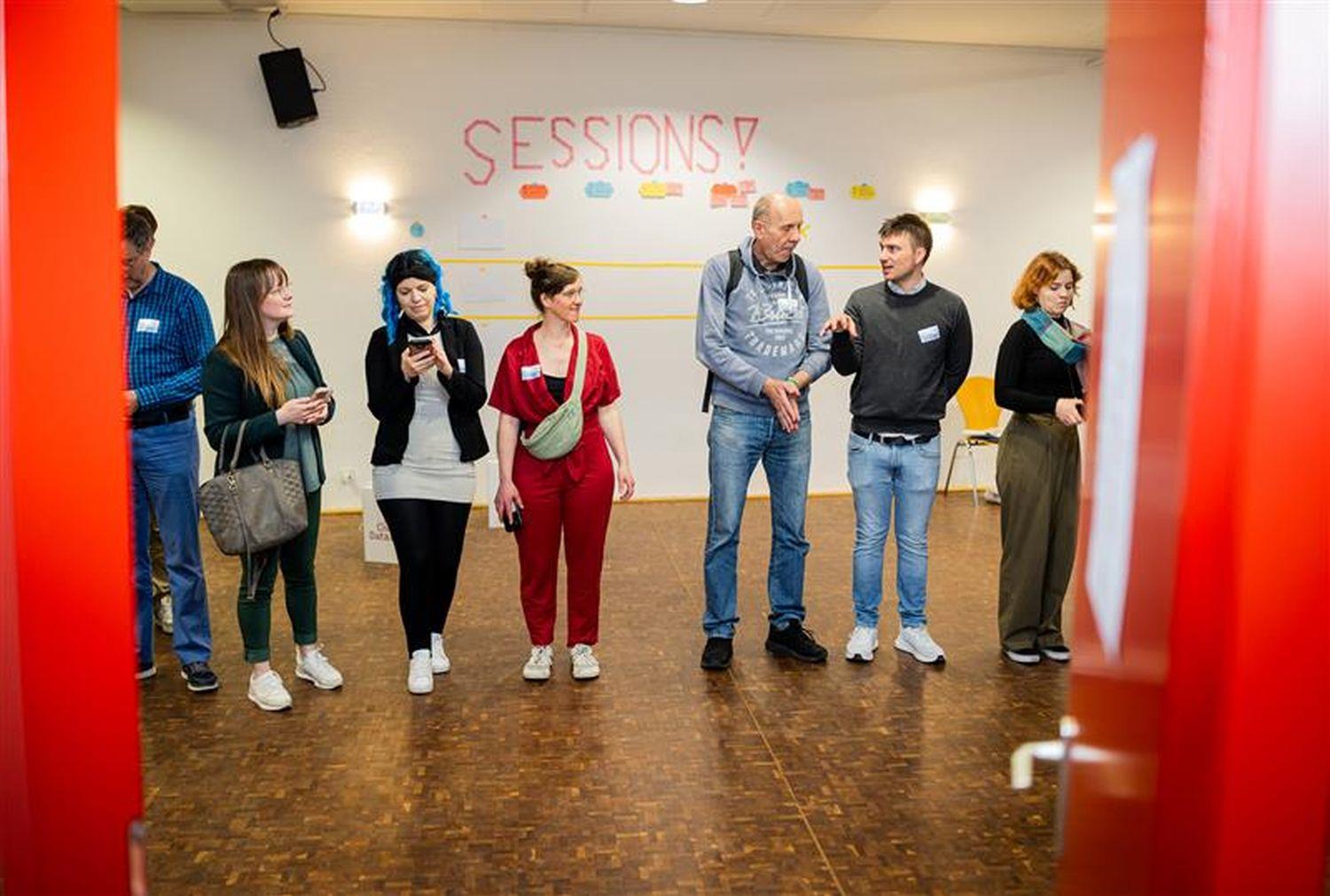 Sieben Teilnehmende der Sessions beim CivicDataLab durch eine rote Kampagnentür fotografiert.