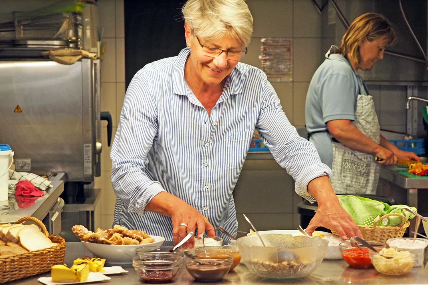 Eine Frau mit kurzen blonden Haaren und Brille steht in einer Küche