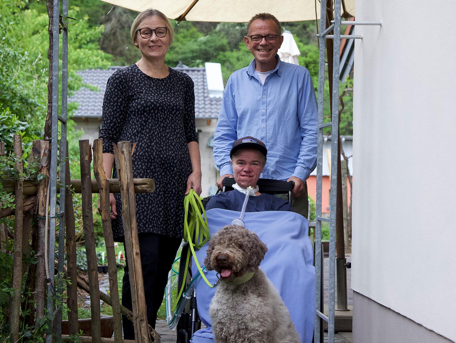 Ein junger Mann im Rollstuhl und ein älteres Ehepaar.