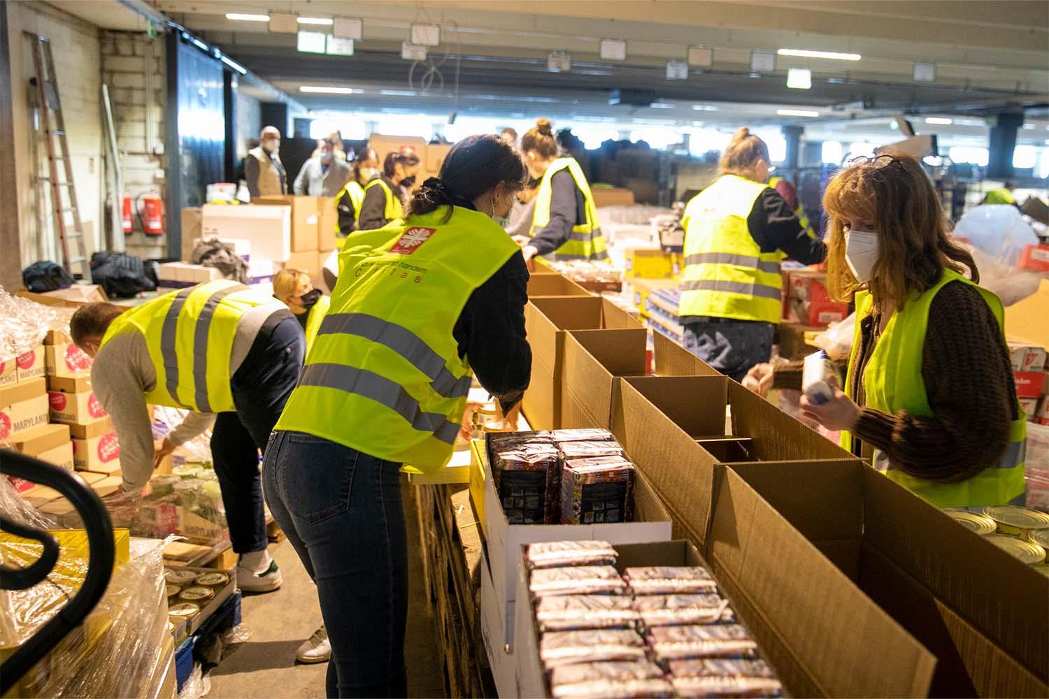 Menschen packen Lebensmittel in Kartons.
