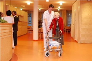 Pfleger Hilft alter Dame im  Heim über den Flur