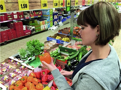 Junge Frau beim Gemüseauswählen im Supermarkt