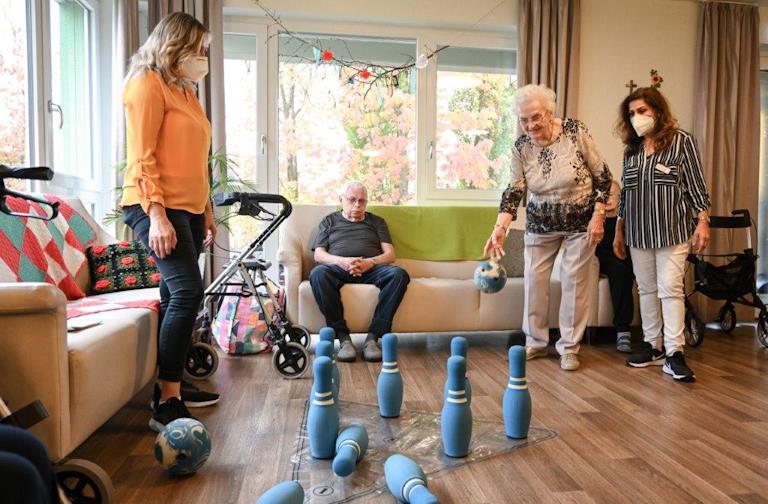 Menschen in einer Pflegeeinrichtung kegeln.