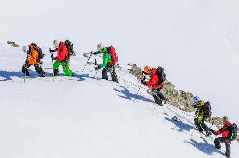 Eine Seilschaft kämpft sich durch den Schnee.