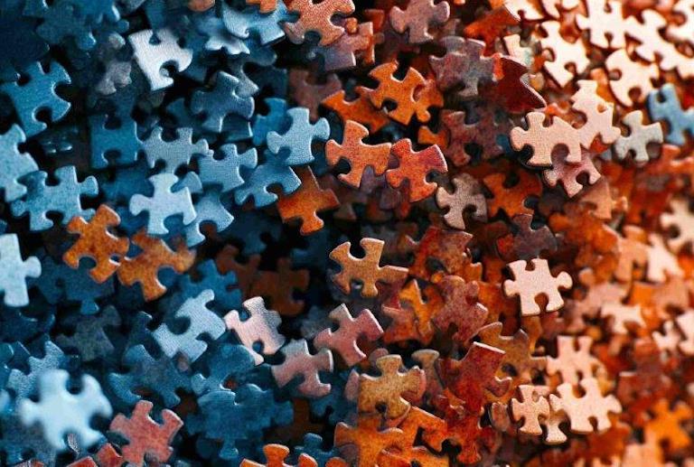 Viele unsortierte Puzzleteile in Blau- und Rottönen.