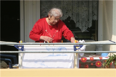 Ältere Dame hängt Wäsche auf Wäscheständer
