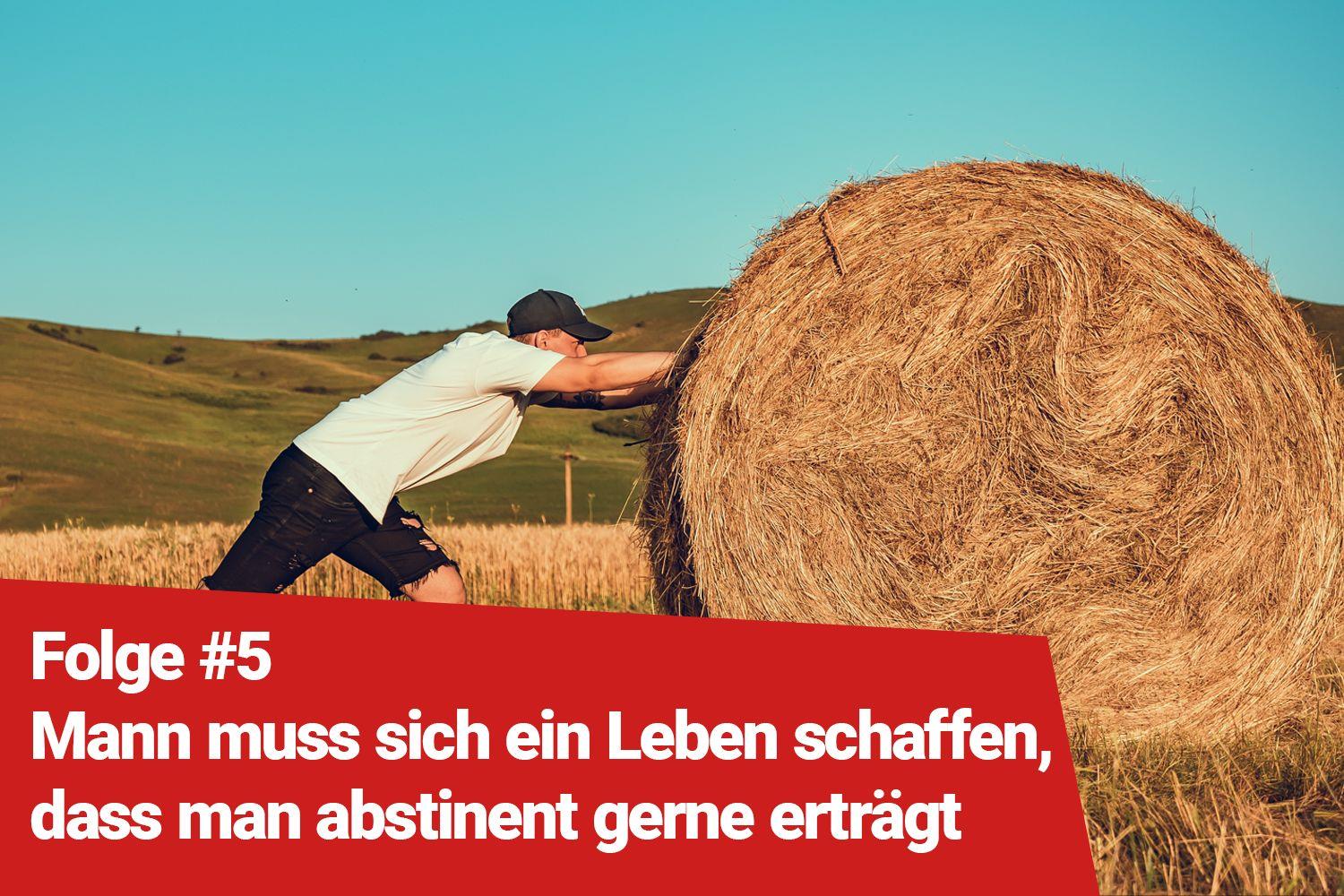 Mann schiebt einen Heuballen vor sich her.