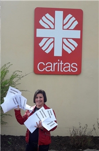 Frau mit Blättern in der Hand vor Caritas-Logo