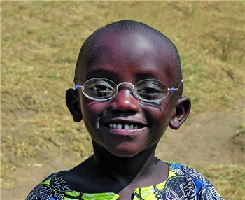 Ein Junge mit Brille grinst in die Kamera.
