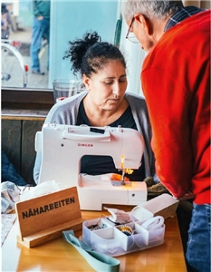 Eine ehrenamtliche Mitarbeiterin des Repair-Cafés an der Nähmaschine.