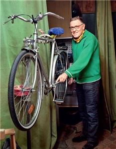 Ein ehrenamtlicher Mitarbeiter des Repair-Cafés hebt ein repariertes Fahrrad.