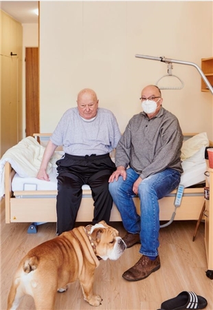 Bewohner Erwin Kramny mit Sohn Gregor im Pflegezimmer - der Hund ist mit dabei.