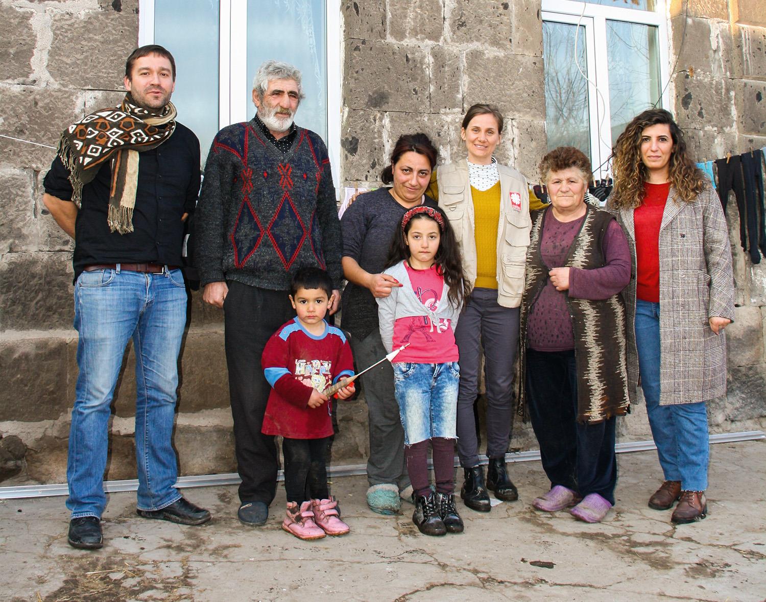 Familie Tonoyan posiert gemeinsam mit Martin Thalhammer (links) und weiteren Mitarbeitenden der Caritas vor ihrem Haus in Haykavan.